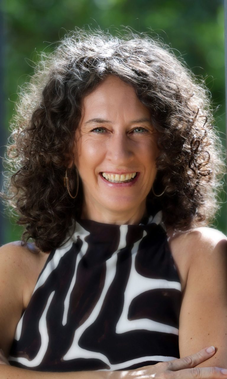 Yvonne Schwarz orträt von Yvonne Schwarz, Coaching und Energetic Health, warmes Sepia-Schwarz-Weiß-Foto mit lockigem Haar und offenem Lächeln